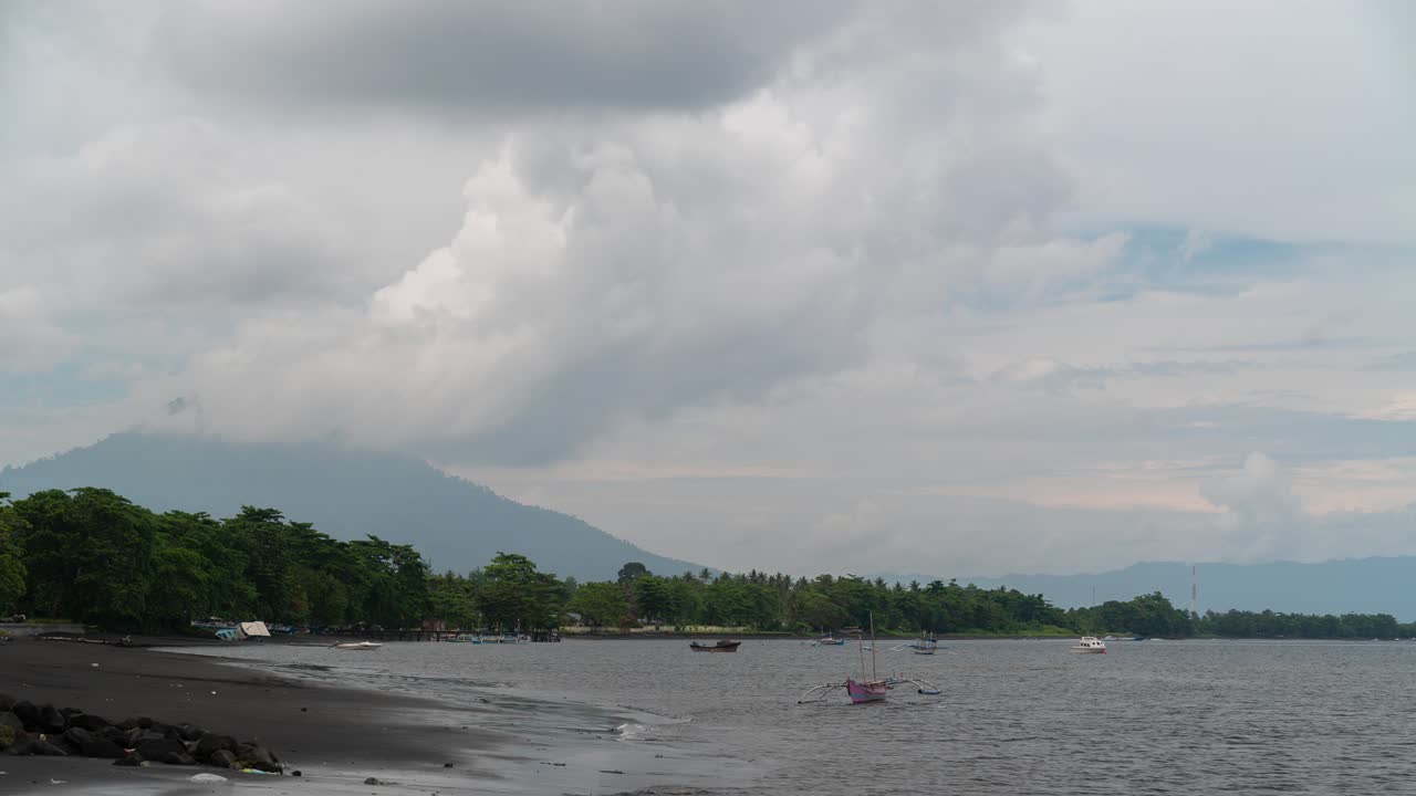 Coastal landscape with boats and mountains under a cloudy sky