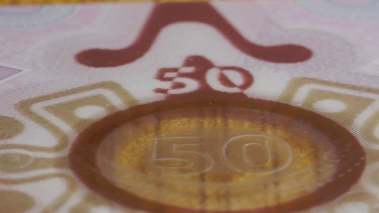 Meksika 50 peso banknotu üzerinde hareket eden yakın çekim kaydırma görüntüsü, karmaşık baskılı desenleri, büyük kupür numaralarını, ince detayları ve güvenlik unsurlarını ortaya çıkarıyor.