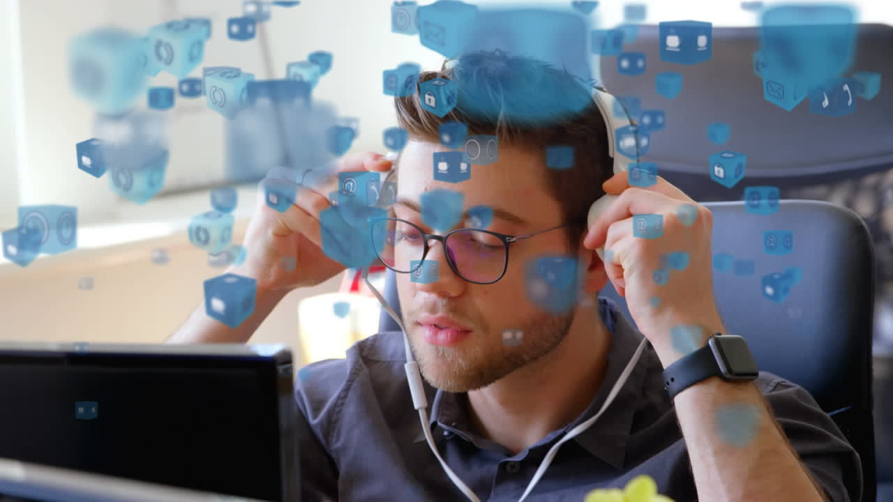 Animation of blue icons flying over a man working at home and using earphones