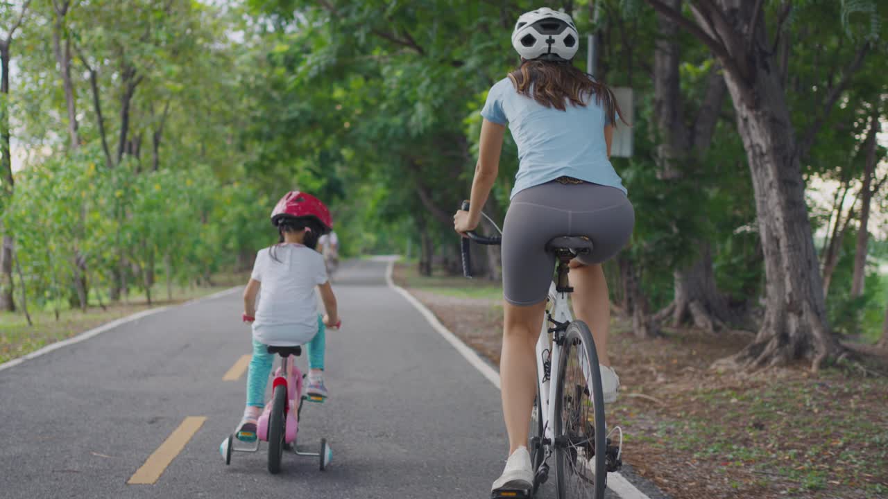 어머니 와 딸 이 공원 에서 자전거 타기 를 즐기고 있다