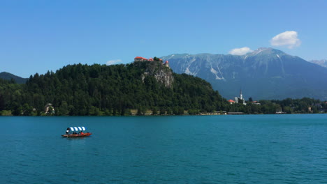 boatman rowing a traditional pletna boat with tourists in bled lake - boat cruise to bled island in slovenia