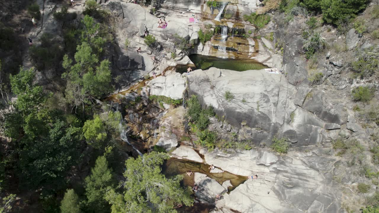 vista circular aérea sobre la gente tomando el sol en las rocas, en la cascada fecha de barjas