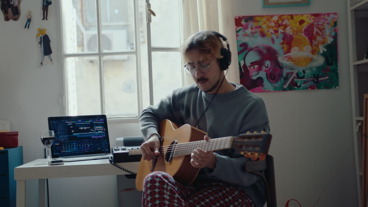 Musician in Headphones Playing the Guitar and Singing at Home Studio