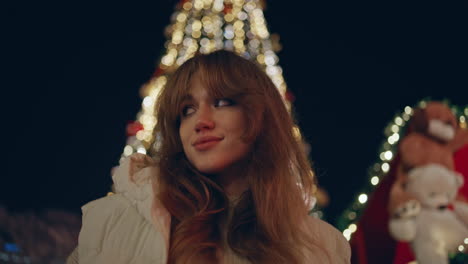 niña posando decoración de luces de navidad en la calle nocturna de primer plano. mujer feliz