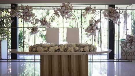 minimalist wedding table setup with floral accents and backdrop of greenery filled windows