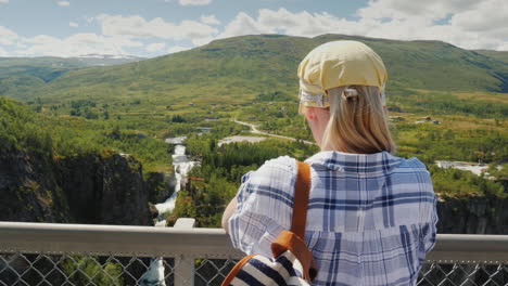 a woman looks at the majestic waterfall of woringsfossen in norway impressive beauty of scandinavian