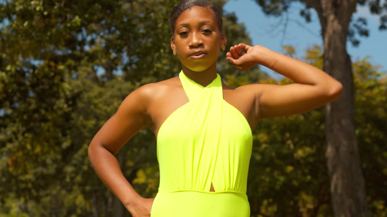 una niña juega con su cabello en un bikini tanga mientras está de pie en un parque