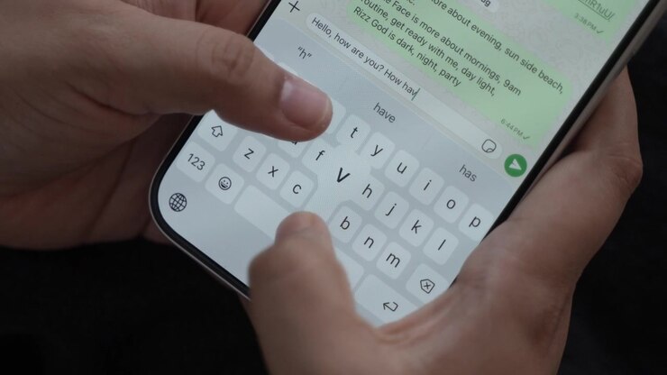 Woman's hand chatting and typing on a smartphone, macro closeup. Unrecognisable human typing a text message, tapping the touchscreen keyboard using the WhatsApp application, a social media.
