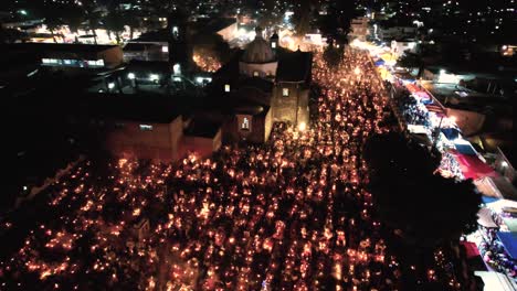 flying over the cemetery and church of mixquic, candles and smoke can be seen over the tombs on the day of the dead