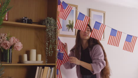 mujer en casa colgando estrellas americanas y rayas bandera bunting para la fiesta celebrando el 4 de julio día de la independencia 6
