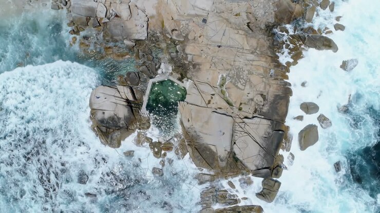 Composizione digitale di forme geometriche astratte fluttuanti su vista aerea delle onde del mare