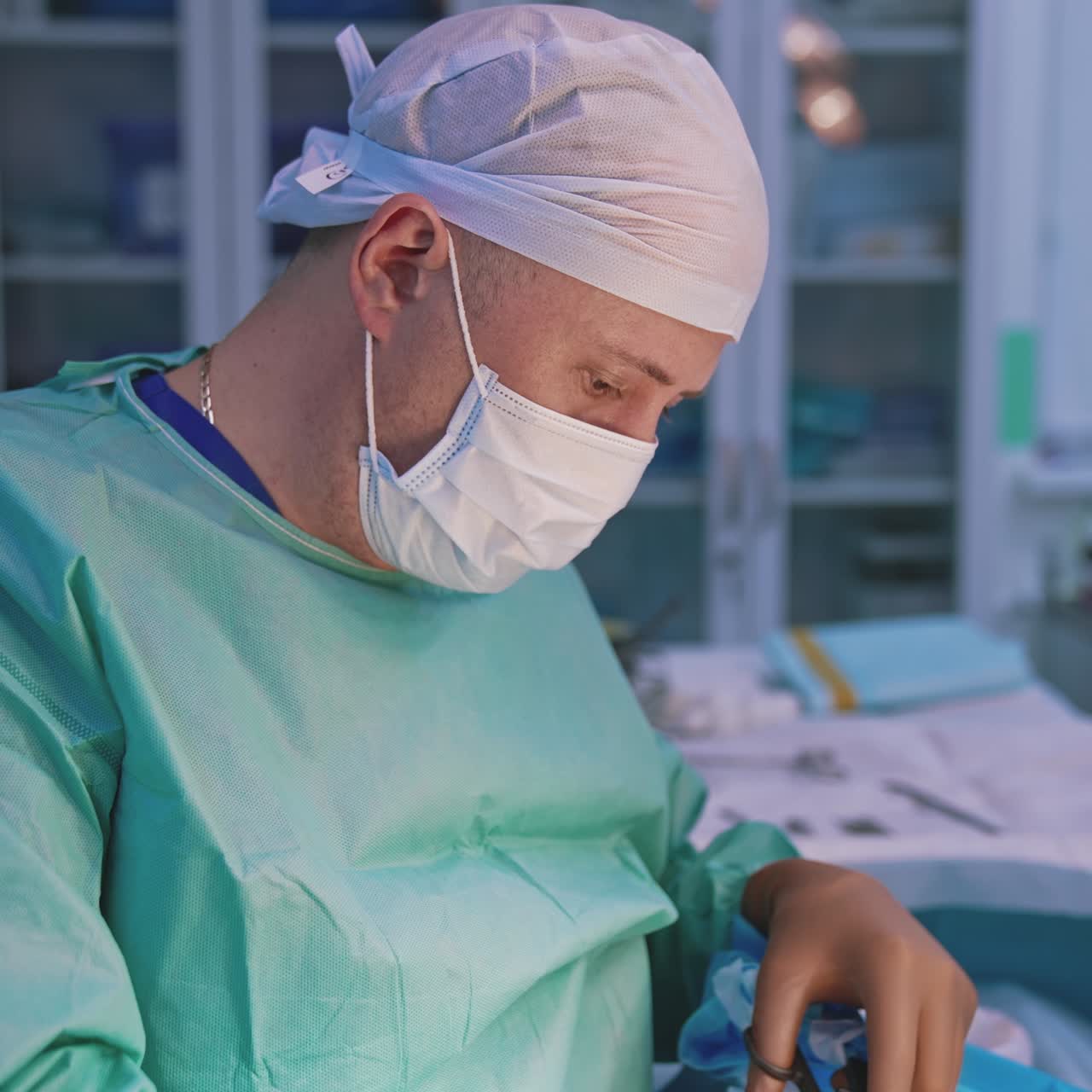 Surgeon is doing plastic surgery. Professional doctor in medical mask and uniform working with surgical scissors during operative process in clinic