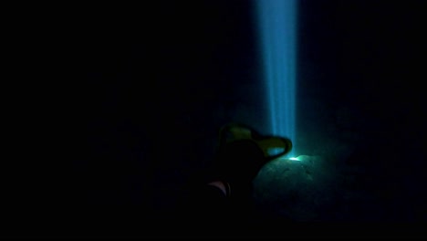 skuba diver exploring the dark water of a sea cave with a natural beam of sun light illuminating rocks underwater in a mysterious atmosphere, vis island, adriatic sea, croatia