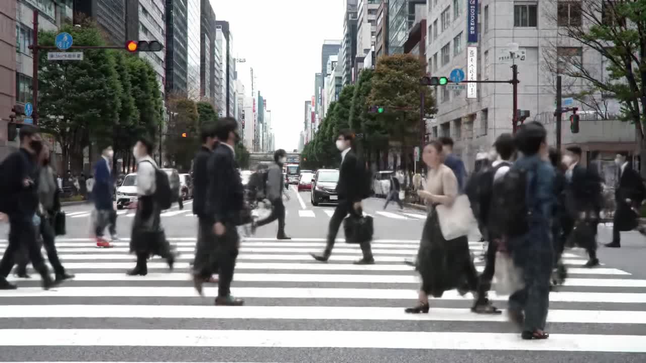 A Busy Urban Intersection Overflowing with Pedestrians Traversing a Striped Crosswalk Amidst High-Rise Buildings and Traffic Flowing in a Metropolitan City
