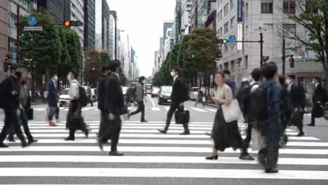 a busy urban intersection overflowing with pedestrians traversing a striped crosswalk amidst high-rise buildings and traffic flowing in a metropolitan city