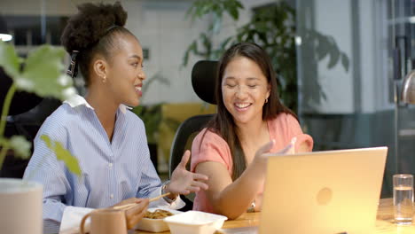 young african american woman and biracial woman collaborate in a business office setting