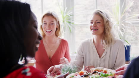 two young adult white women eating lunch with friends at a restaurant, over shoulder view, close up