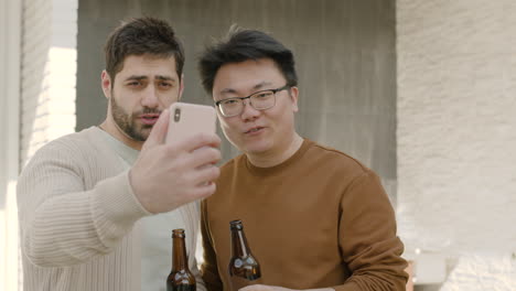 a young guy and his friend make a videocall while drinking beers