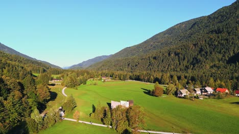 forestry alps slopes and small town bellow on sunny warm day, aerial view