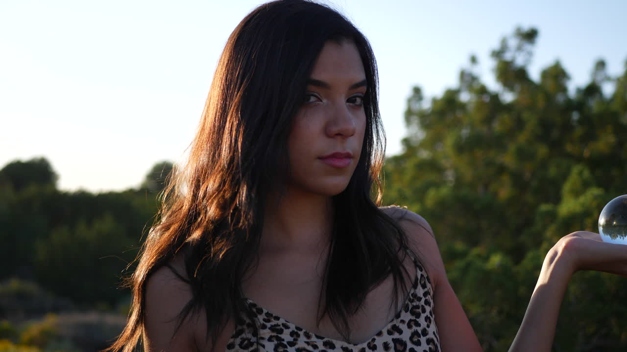 마법의 크리스탈 볼과 관능적인 응시 슬로우 모션을 가진 신비로운 환상의 세계에 있는 아름다운 꿈꾸는 히스패닉 여성