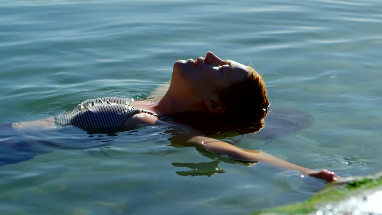mujer nadando en el agua en la playa 4k