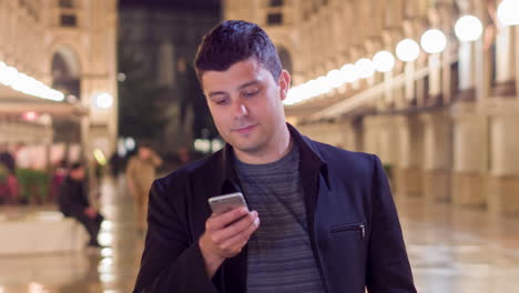 hombre usando un teléfono inteligente por la noche en una ciudad