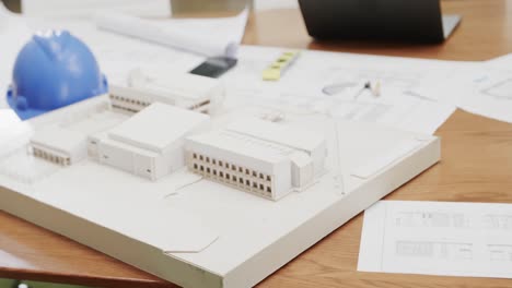 close up of model of building and helmet on table in architects' office in slow motion