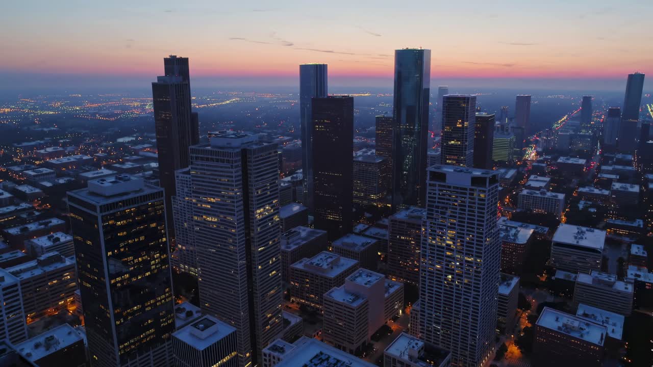 Un video aereo cattura lo skyline di una città al tramonto, con una vista a bassa angolazione che mette in risalto le silhouette