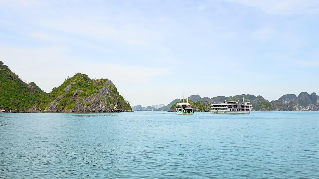 Luxury cruise ships gracefully navigate through the emerald waters of Ha Long Bay, surrounded by towering limestone karsts and lush green islands that create a breathtaking seascape in Vietnam