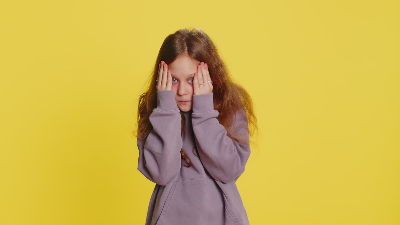 Curious preteen child girl kid closing eyes with hand and spying through fingers hiding and peeping