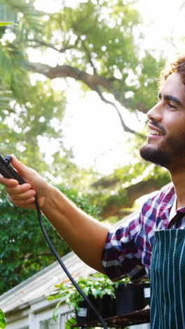 hombre regando la planta con rociador de jardín