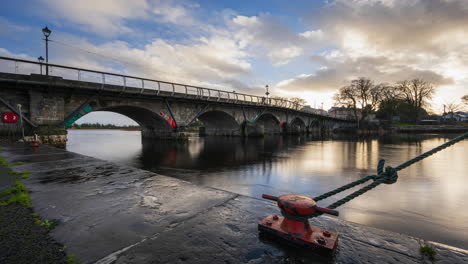 Timelapse-of-Carrick-on-Shannon-town-bridge-in-county-Leitrim-and-Roscommon-with-traffic,-people-and-moving-sunset-evening-clouds-on-river-Shannon-in-Ireland