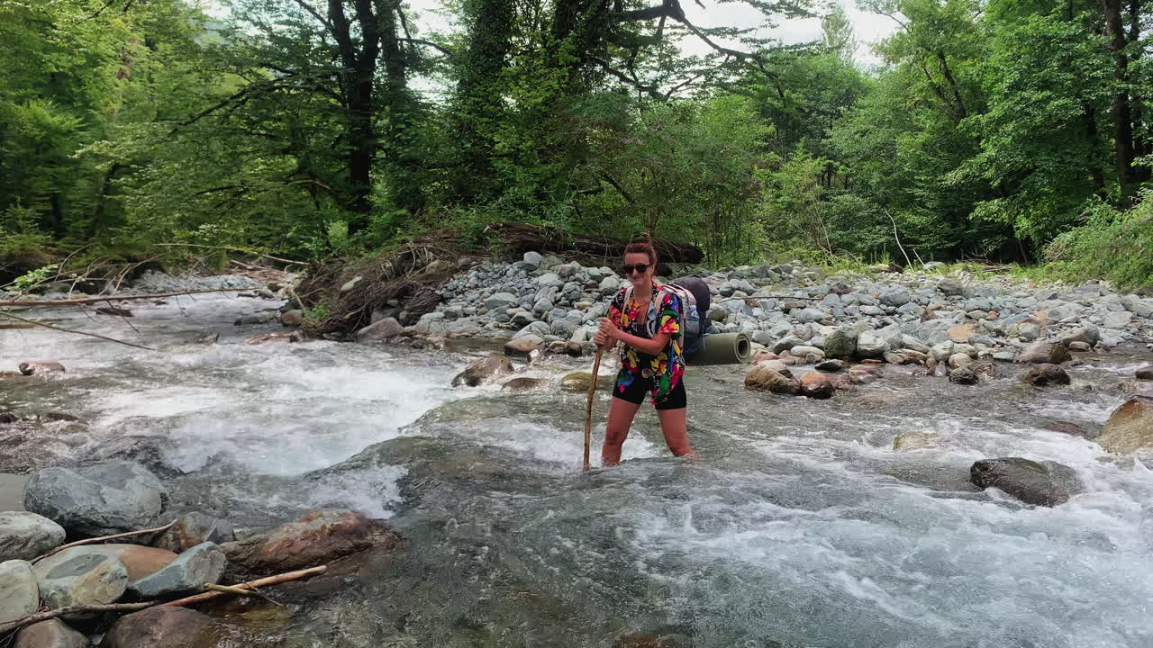 Woman hiking through a river in a forest