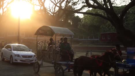 horse drawn carriage being ridden down sunset lit street in chittagong. slow motion