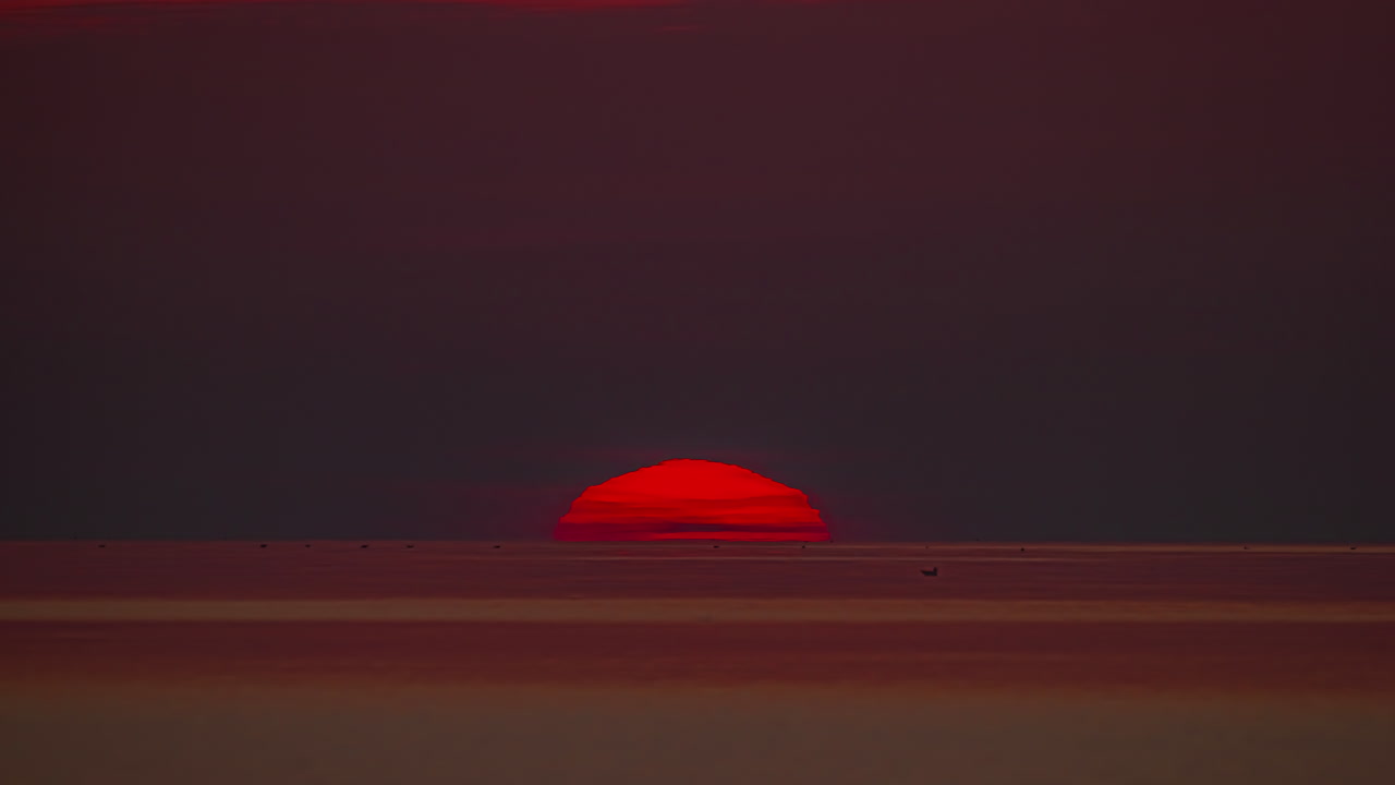 статический снимок солнца, восходящего на рассвете над тихим океаном по красочному красному небу над морскими волнами в утреннее время