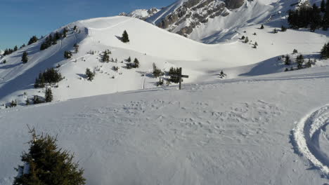 Luftaufnahme,-Die-Im-Winter-über-Einen-Schneebedeckten-Hügel-Mit-Einem-Holzkreuz-Oben-In-Den-Französischen-Alpen-Fliegt