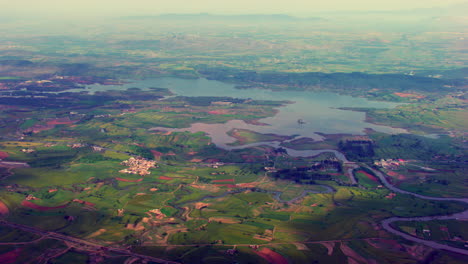 aerial view of a beautiful village near river with green farms, narrow streets and a wriggling river