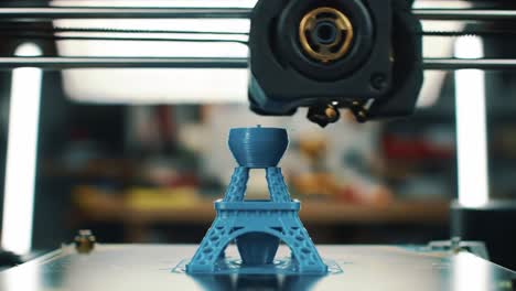 a detailed look at a 3d printer as it progressively constructs a blue miniature tower model, showcasing intricate layers and precision in additive manufacturing