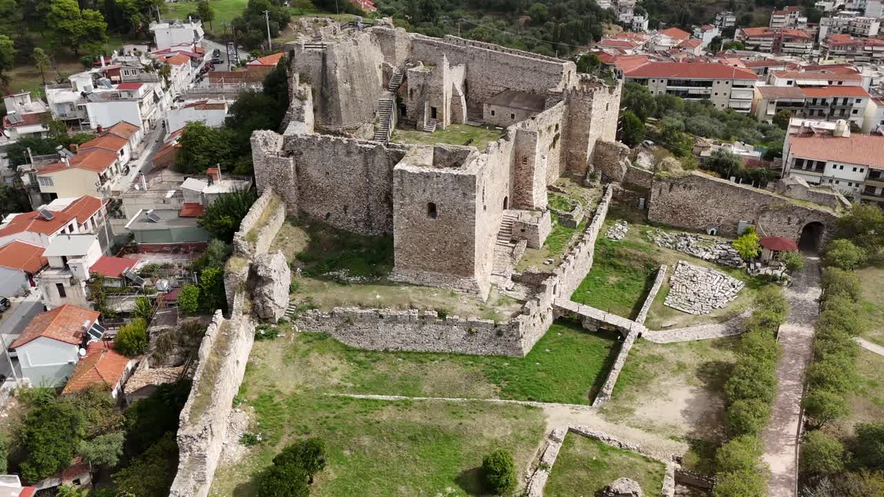 Castello di Patrasso, vista aerea all'indietro ravvicinata dell'edificio principale del castello in una giornata di sole. All'interno tutto verde, circondato da mura e bastioni bianchi. Edifici circondano il vecchio castello