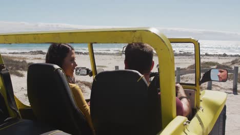 Happy-caucasian-couple-sitting-in-beach-buggy-by-the-sea-talking