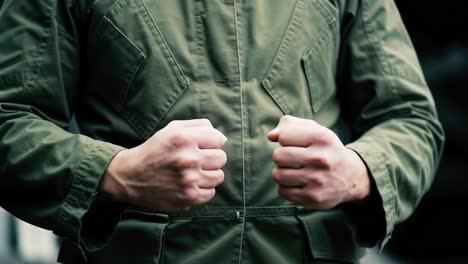 a close-up shot of a person's clenched fists depicting emotion and determination in a military-inspired outfit