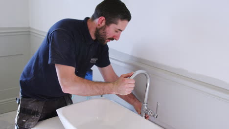 fontanero posicionando los grifos del lavabo en el baño nuevo