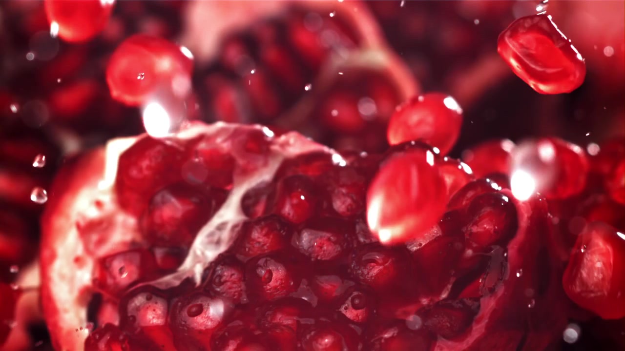 Levende røde granatæblekerner falder i slowmotion