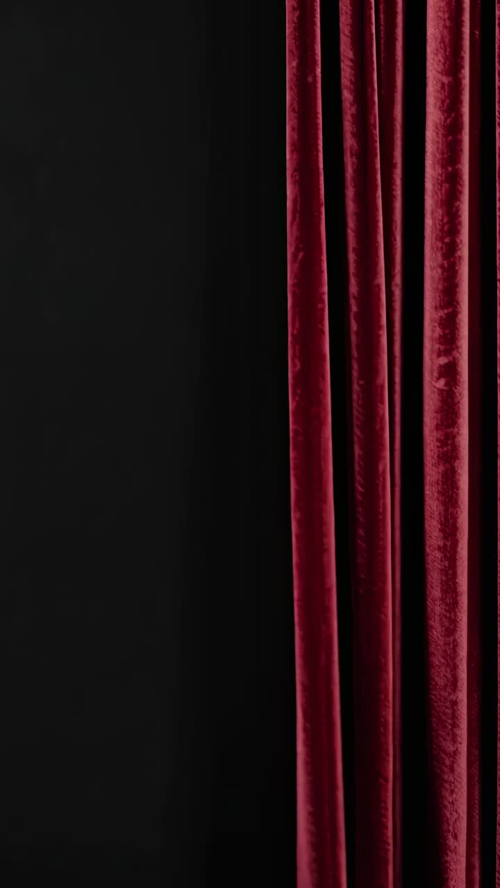 Primo piano di eleganti tende di velluto rosso su sfondo nero, che suggerisce un video teatrale