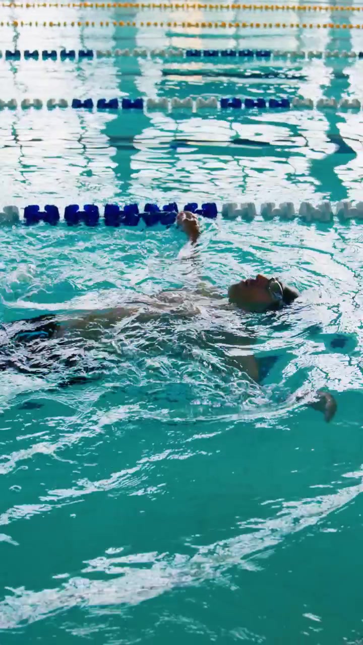 Young Man Swimming Backstroke in Indoor Pool