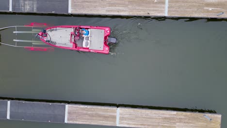 Una-Vista-Desde-Arriba-De-Un-Barco-Pesquero-Rojo-Amarrado-En-Un-Muelle-En-Un-Lago-Tranquilo,-Que-Muestra-Temas-De-Navegación-Y-Puerto-Deportivo.