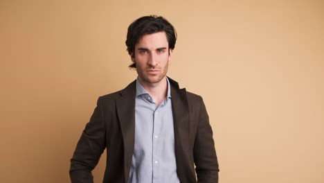 Serious businessman in blazer looking at camera in blue studio