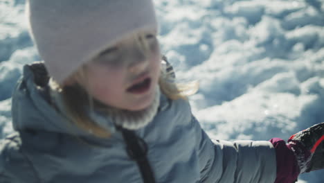 Süßes-Kleines-Blondes-Mädchen,-Das-Bei-Strahlendem-Wintersonnenschein-Schnee-In-Die-Luft-Wirft