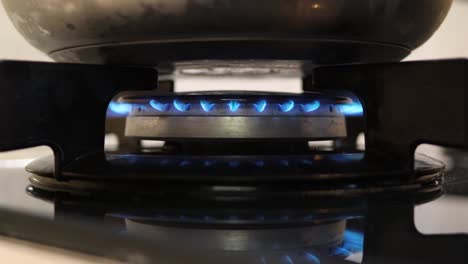 kitchen gas stove ignition and heating a steel pan - blue butane flame close up - daily fossil energy concept