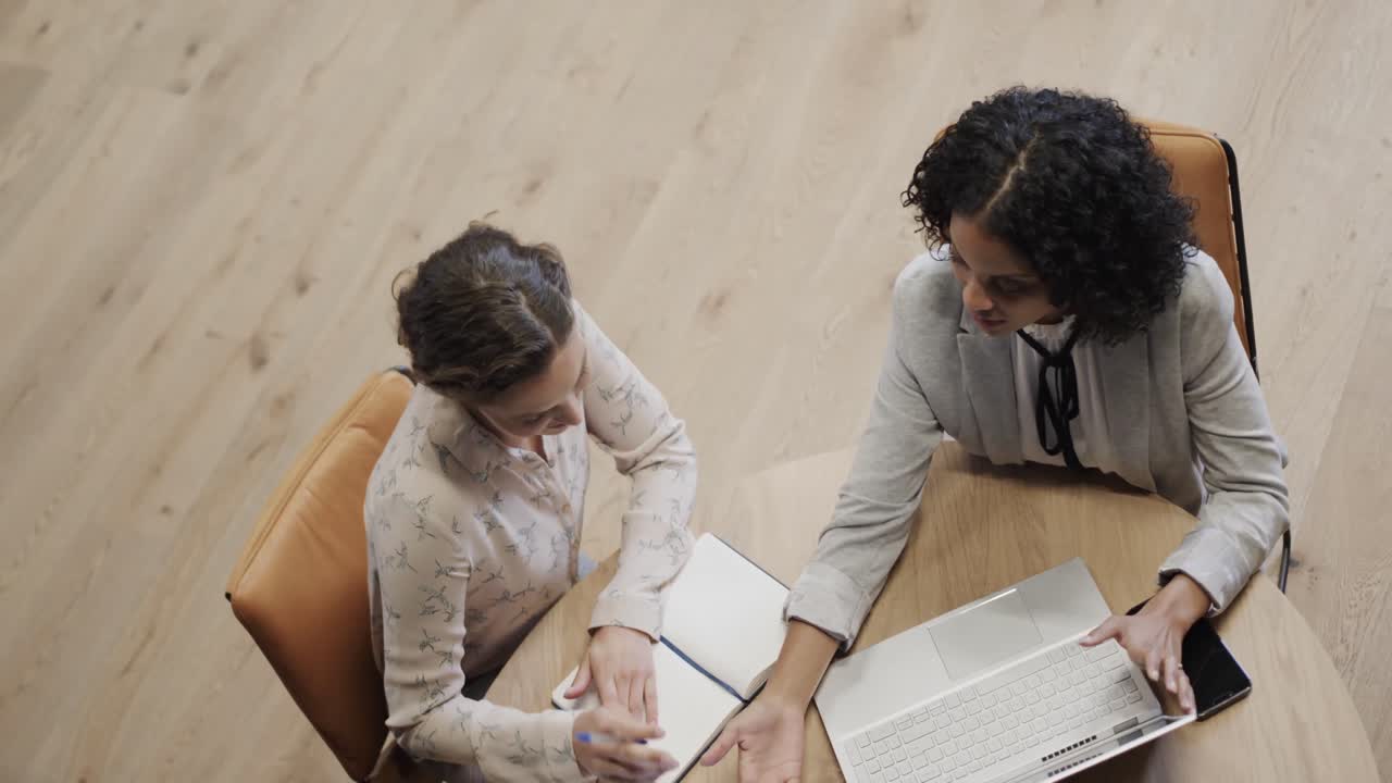 diversas compañeras en discusión usando computadora portátil en el salón de la oficina, cámara lenta